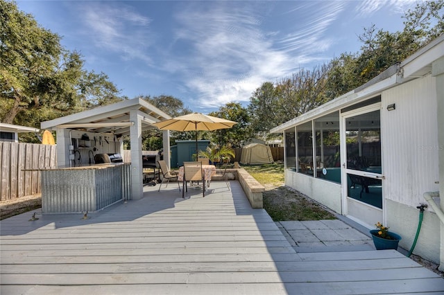 deck with a shed and a sunroom