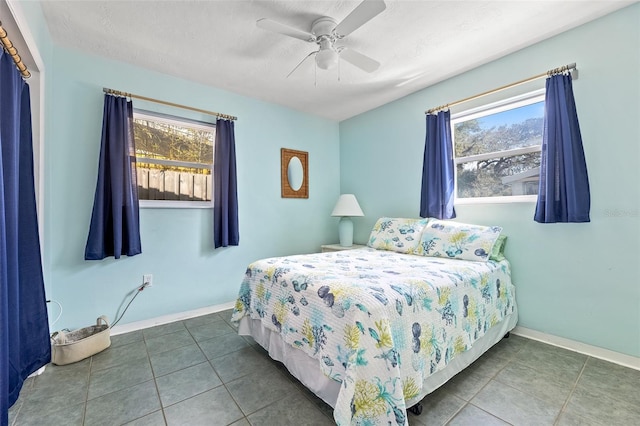 bedroom with multiple windows, dark tile patterned flooring, a textured ceiling, and ceiling fan