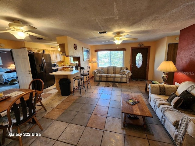 tiled living room featuring a textured ceiling and ceiling fan