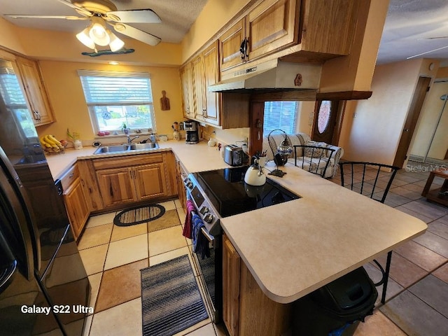 kitchen featuring stainless steel electric range oven, kitchen peninsula, sink, and a breakfast bar area