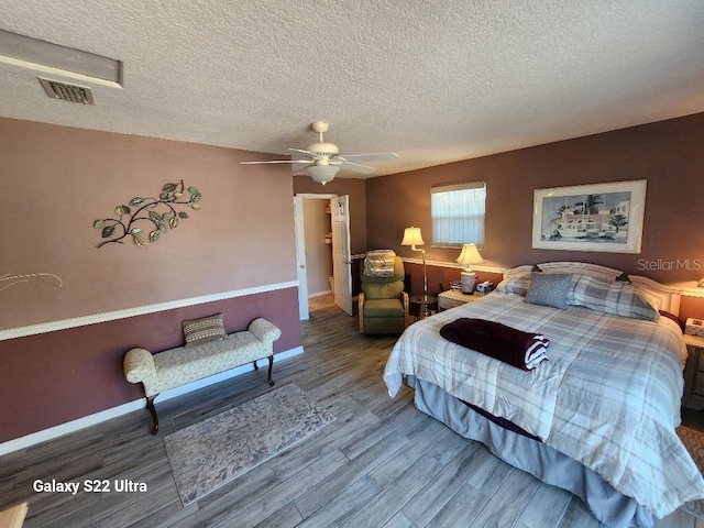 bedroom featuring ceiling fan, wood-type flooring, and a textured ceiling