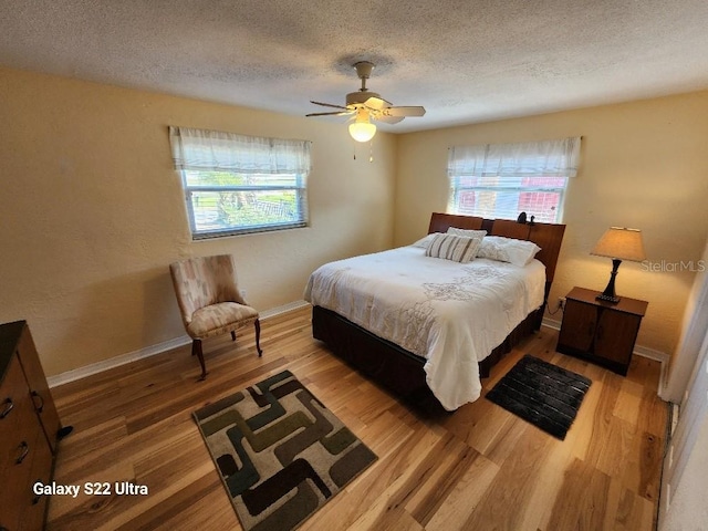 bedroom featuring multiple windows, wood-type flooring, and a textured ceiling