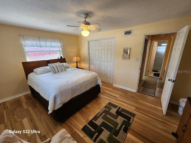 bedroom featuring hardwood / wood-style flooring, ceiling fan, a textured ceiling, and a closet