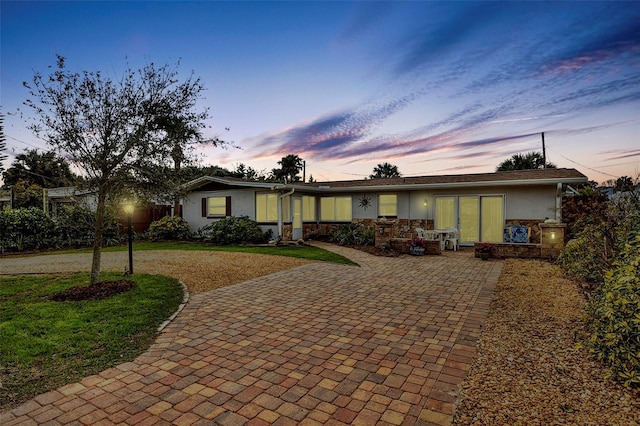 ranch-style house featuring a front yard, decorative driveway, and stucco siding