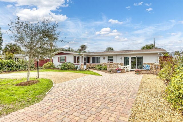 single story home featuring decorative driveway, stucco siding, a front yard, fence, and stone siding