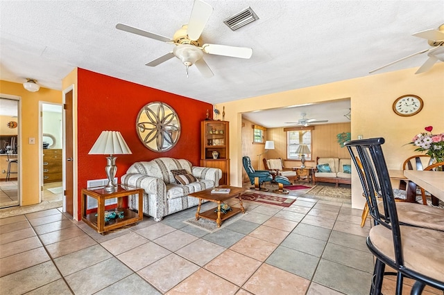 living room with a ceiling fan, visible vents, a textured ceiling, and light tile patterned flooring