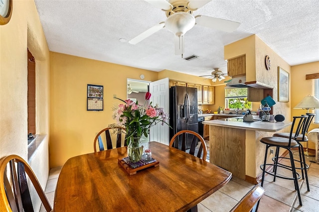 dining area with light tile patterned floors, a textured ceiling, and visible vents