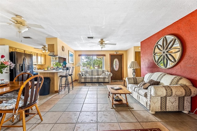 living room with light tile patterned floors, ceiling fan, a textured ceiling, and visible vents