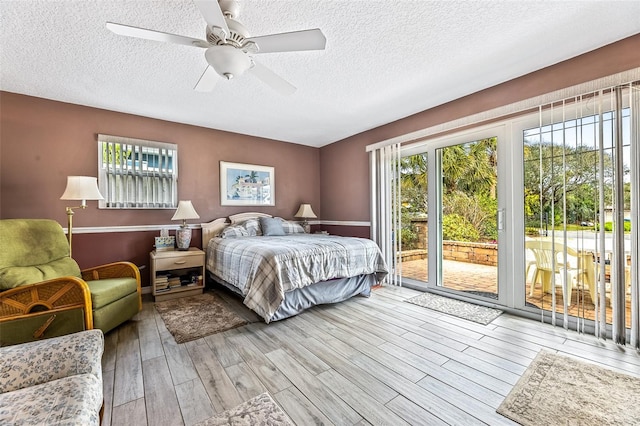 bedroom with light wood-type flooring, access to exterior, a textured ceiling, and a ceiling fan