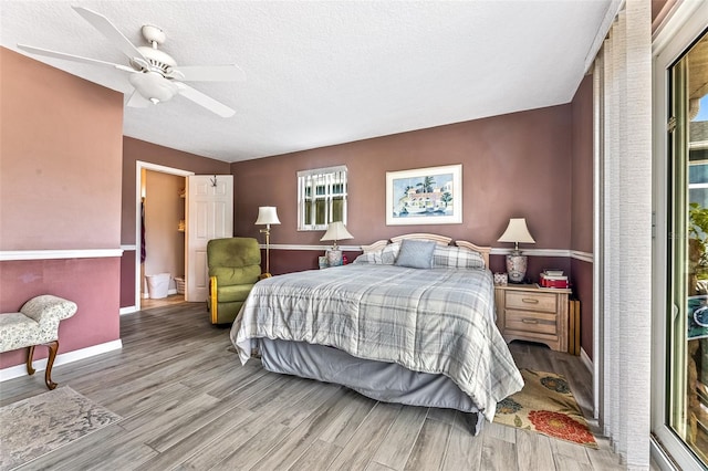 bedroom with a ceiling fan, light wood-style flooring, baseboards, and a textured ceiling