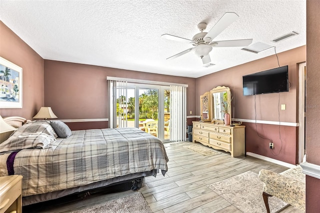 bedroom featuring light wood finished floors, visible vents, a ceiling fan, a textured ceiling, and access to outside