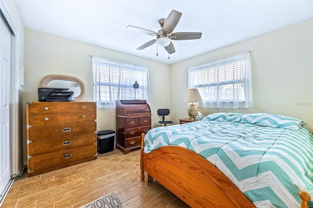 bedroom with a closet, ceiling fan, and light wood-style flooring