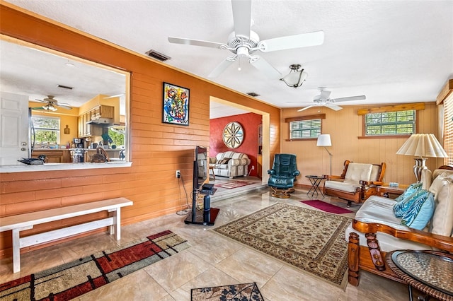 living room with visible vents, wooden walls, and a textured ceiling