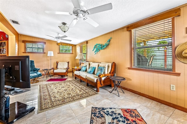 living area featuring a textured ceiling, a wealth of natural light, visible vents, and baseboards