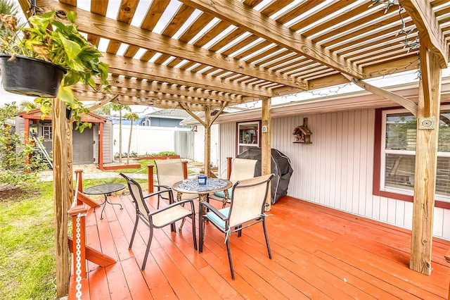 wooden terrace with an outbuilding, a grill, fence, a pergola, and outdoor dining space