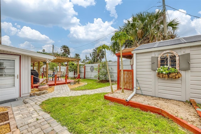 view of yard with fence, a deck, a pergola, and an outdoor structure