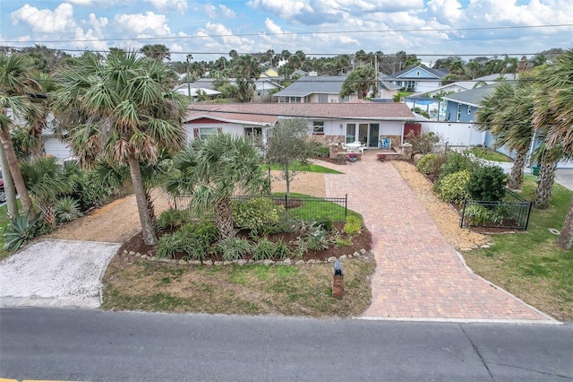 view of front of property featuring decorative driveway, a fenced front yard, and a residential view