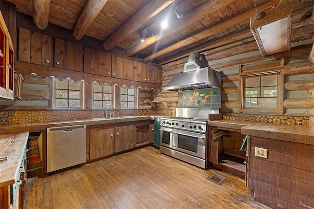 kitchen featuring sink, light hardwood / wood-style flooring, appliances with stainless steel finishes, backsplash, and wall chimney exhaust hood