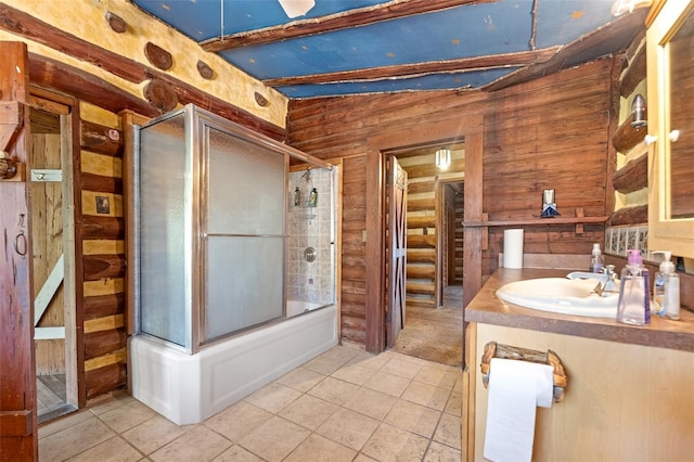 bathroom featuring tile patterned flooring, vanity, combined bath / shower with glass door, and wooden walls