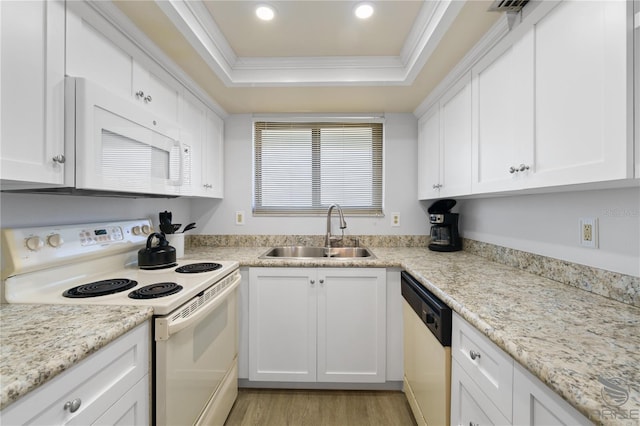 kitchen with a tray ceiling, sink, white appliances, and white cabinets