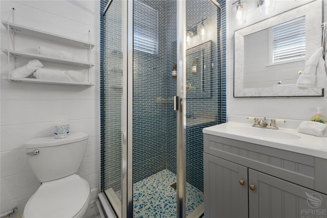 bathroom featuring a shower with door, vanity, and toilet