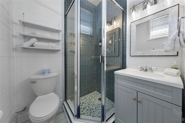 bathroom featuring a shower with door, vanity, and toilet