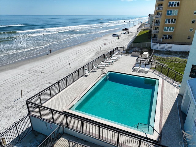 view of swimming pool with a view of the beach, a water view, and a patio