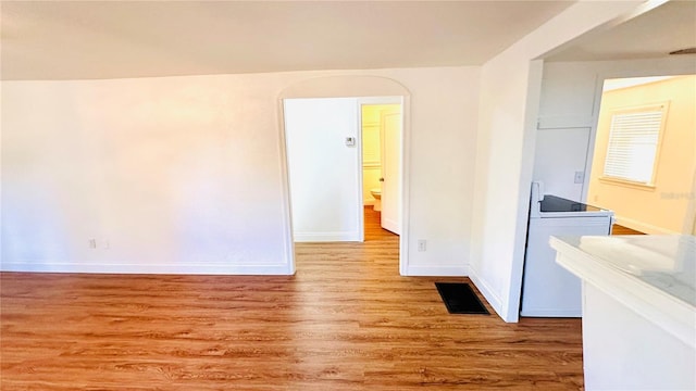 unfurnished room featuring washer / clothes dryer and light hardwood / wood-style flooring