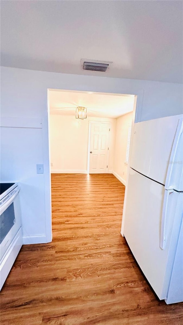 kitchen with light wood-type flooring, white cabinets, and white appliances