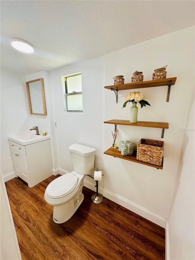 bathroom with vanity, toilet, hardwood / wood-style floors, and a textured ceiling