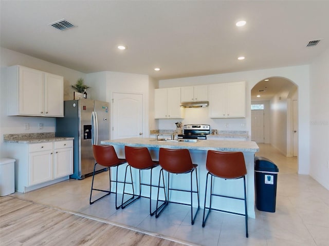 kitchen featuring white cabinetry, appliances with stainless steel finishes, a breakfast bar, and a center island with sink