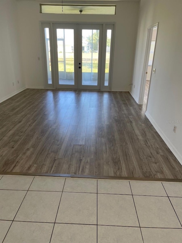 empty room featuring baseboards, french doors, and wood finished floors