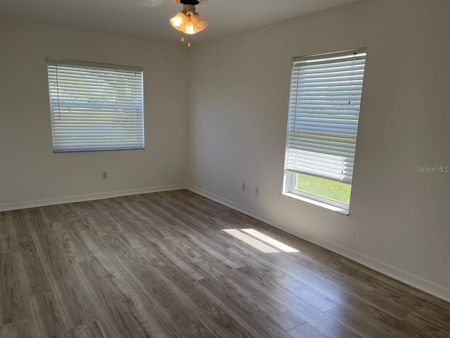 empty room featuring wood finished floors, baseboards, and ceiling fan