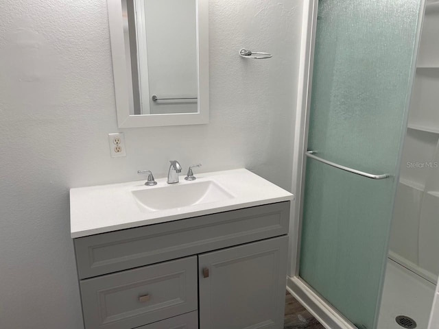 bathroom featuring wood finished floors, vanity, and a stall shower