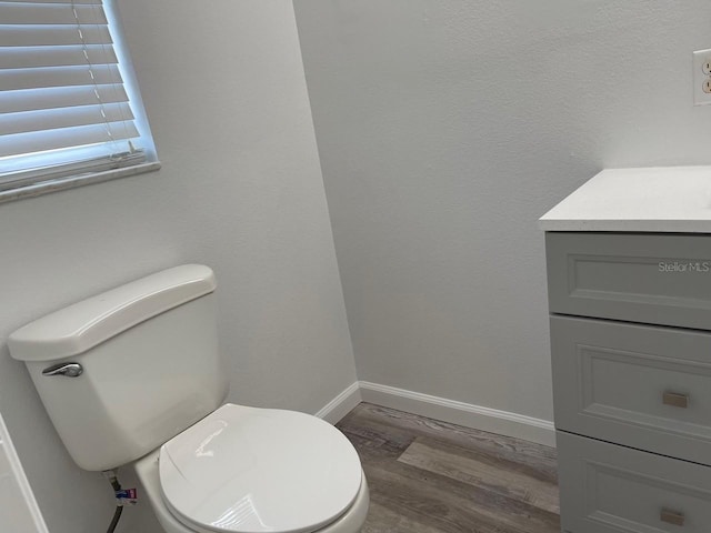bathroom featuring baseboards, wood finished floors, vanity, and toilet