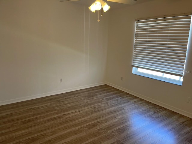 spare room featuring a ceiling fan, baseboards, and dark wood-style flooring