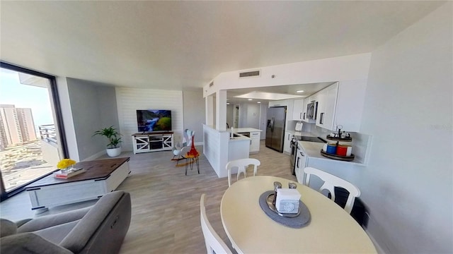 dining room featuring floor to ceiling windows, sink, and light wood-type flooring