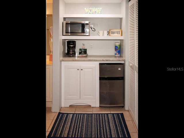 bar with light tile patterned floors and appliances with stainless steel finishes