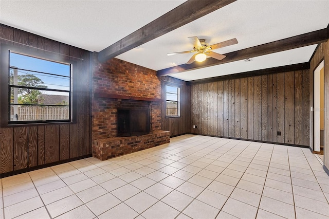 unfurnished living room featuring beam ceiling, a textured ceiling, and wood walls