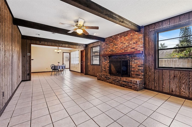 unfurnished living room featuring a brick fireplace, wooden walls, beam ceiling, and a textured ceiling