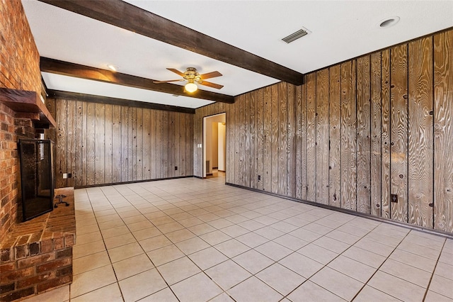 unfurnished living room with beamed ceiling, light tile patterned floors, and wood walls