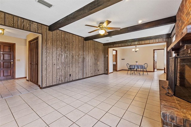 unfurnished living room with light tile patterned flooring, wood walls, a textured ceiling, beam ceiling, and ceiling fan with notable chandelier