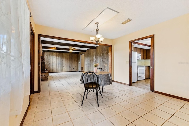 unfurnished dining area featuring an inviting chandelier, wood walls, and light tile patterned floors