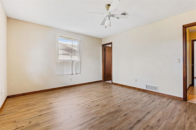 empty room with a textured ceiling, light hardwood / wood-style floors, and ceiling fan