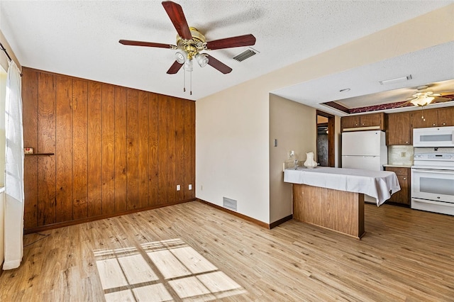 kitchen with white appliances, a textured ceiling, light wood-type flooring, kitchen peninsula, and ceiling fan