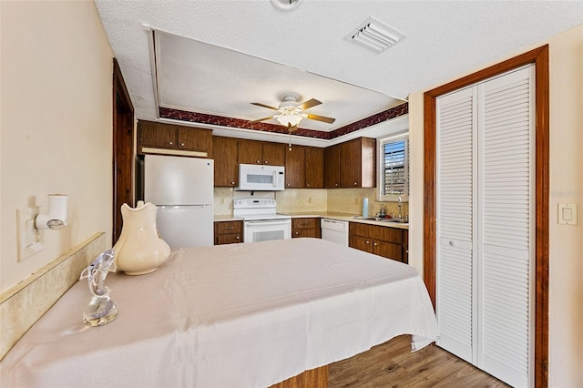 kitchen featuring wood-type flooring, sink, ceiling fan, kitchen peninsula, and white appliances