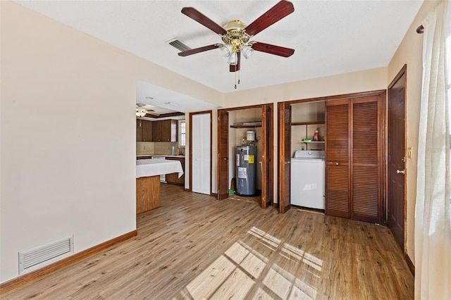 unfurnished living room with washer / clothes dryer, wood-type flooring, water heater, and ceiling fan