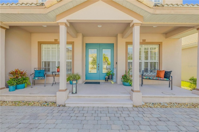 view of exterior entry featuring a porch and french doors