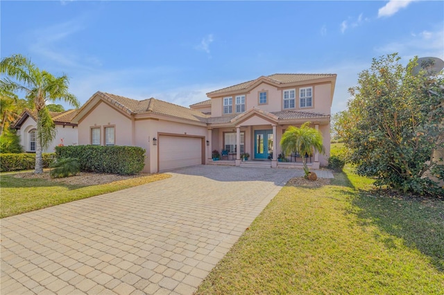 mediterranean / spanish house featuring a garage, a front yard, and covered porch