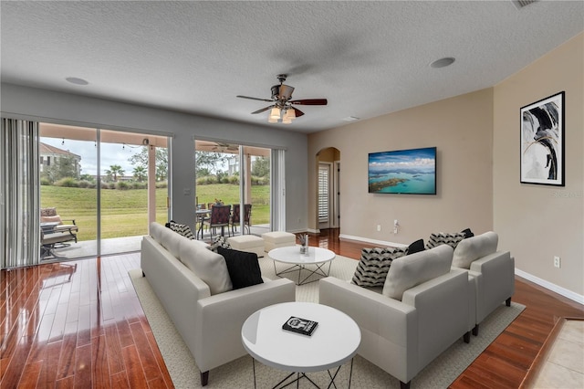 living room featuring ceiling fan, wood-type flooring, and a textured ceiling